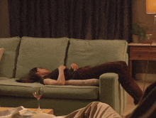 a woman is laying on a couch with a glass of wine