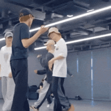 a group of people are dancing in a room with a man wearing a hat