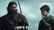 a man holding a bow and arrow says he 's ready next to a young boy
