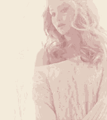 a woman with long blonde hair wearing a white sweater looks down