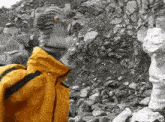 a man in a yellow jacket is standing next to a statue of a woman