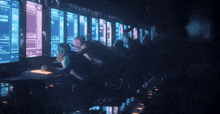 a group of people are sitting in front of computer monitors .