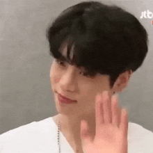 a young man in a white shirt is waving his hand .