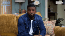a man sitting on a couch with a bet logo on the bottom