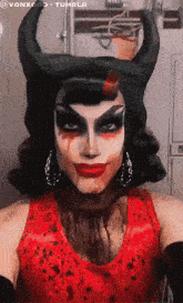 a woman in a devil costume with horns and blood on her face