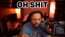 a man is sitting in front of a microphone with the words oh shit written above him