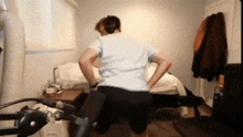 a man wearing headphones is doing squats on a treadmill
