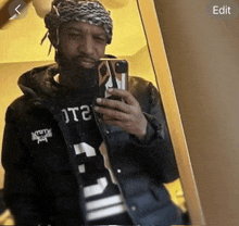 a man with a beard is taking a selfie in a mirror with his phone .
