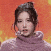 a close up of a woman wearing a purple sweater and a microphone on a stage .