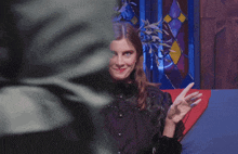 a woman sitting in front of a stained glass window making a funny face