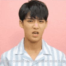 a young man wearing a striped shirt is making a funny face