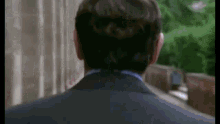 a man in a suit and tie is walking down a sidewalk .
