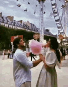 a man is giving a woman cotton candy at a carnival .