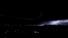 a lightning bolt is visible in the night sky above a city
