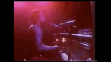 a man is playing a piano on a stage in front of a purple background .