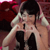 a woman making a heart shape with her hands in front of a pink and white chair that says jusno on it
