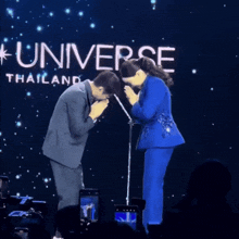 a man in a suit bows to a woman in front of a sign that says universe