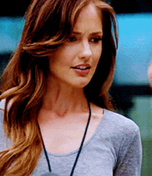 a woman with long hair is wearing a gray shirt and a lanyard around her neck