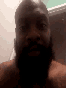 a man with a beard and a tattoo on his arm looks down