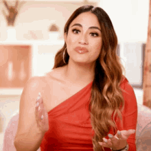 a woman in a red one shoulder dress is talking