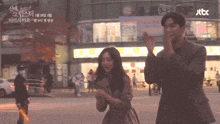 a man and woman are clapping in front of a building that says jtbc on it