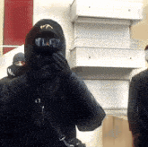 a man wearing sunglasses and a hood with the letter t on it