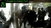 a group of people are standing in front of a sign that says caught on kopizz cam