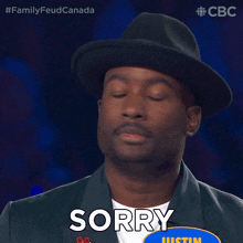 a man wearing a hat says sorry in front of a sign that says justin