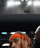 a man with dreadlocks wearing an orange headband and earbuds