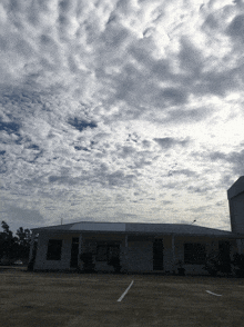 a building under a cloudy sky with a parking lot in front of it