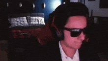 a man wearing headphones and sunglasses is sitting in a dark room
