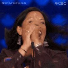 a woman is laughing and clapping in front of a microphone with a cbs logo in the corner