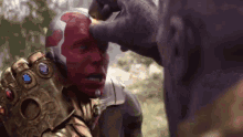 thanos is holding a helmet on vision 's head in a superhero movie .