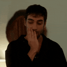 a man with a beard is covering his mouth with his hand