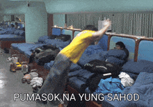 a man in a yellow shirt is jumping on a bed with the words pumasok na yung sahod written below him