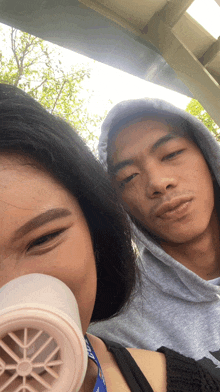 a man and a woman are posing for a picture with the man wearing a grey hoodie and the woman wearing a black tank top