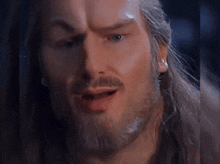 a close up of a man with long hair and a beard making a face .