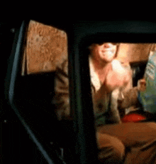 a man is sitting in a car eating a sandwich and drinking a beer .