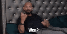 a bald man is laying on a bed with his arms outstretched and the words wen written above him .
