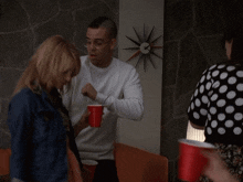 a man holding a red cup talks to a woman