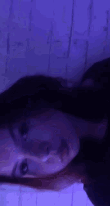 a woman is taking a selfie in front of a purple light .