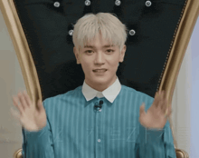 a young man with blonde hair is sitting in a chair