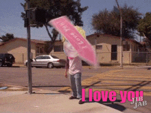 a man holding a pink umbrella that says i love you on it