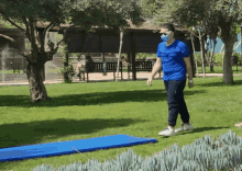 a man wearing a mask and a blue shirt is walking on a blue mat