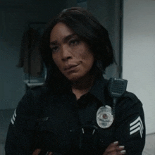 a woman in a police uniform has her arms crossed and a badge on her chest
