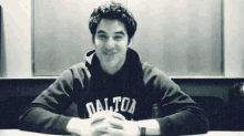 a man in a dalton sweatshirt sits at a table