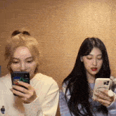 two girls are looking at their cell phones and one has a case that says happy rabbit on it