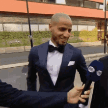a man in a tuxedo is being interviewed by a man holding a microphone that says fox
