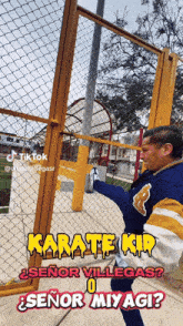 a man in a blue jacket is kicking a chain link fence with the caption karate kid