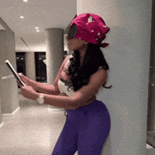 a woman wearing purple pants and a pink headband is using a tablet